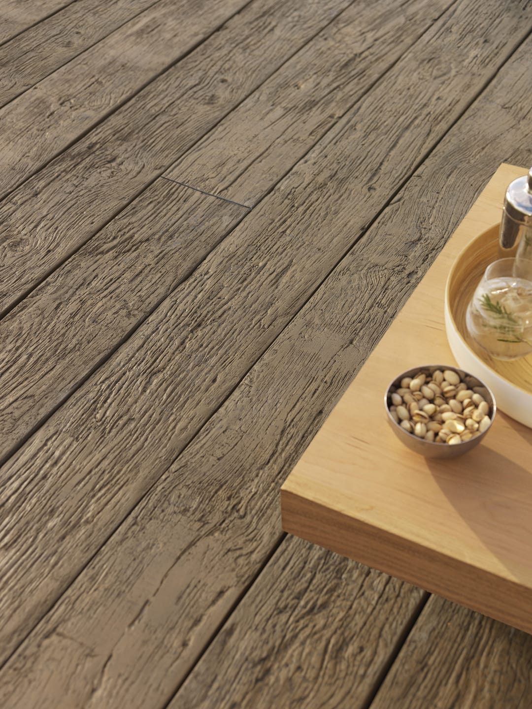 Close view of rough-textured brown Vintage decking with a timber side table holding a bowl of nuts and a carafe