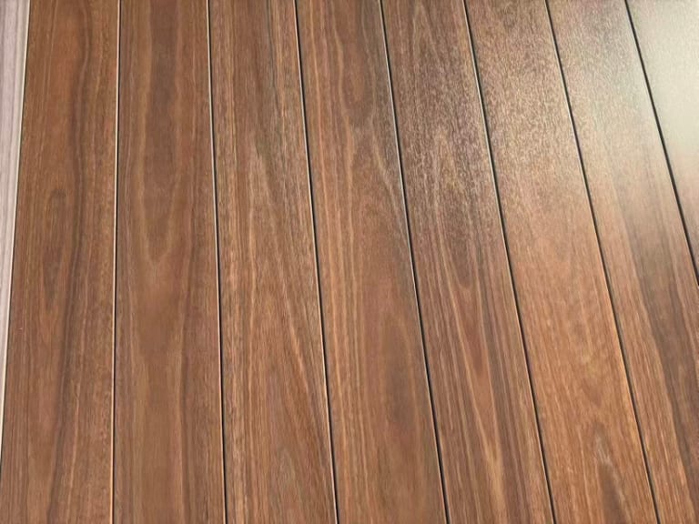Close-up of laid Origin American Black Walnut composite deck boards in deep reddish-brown walnut grain