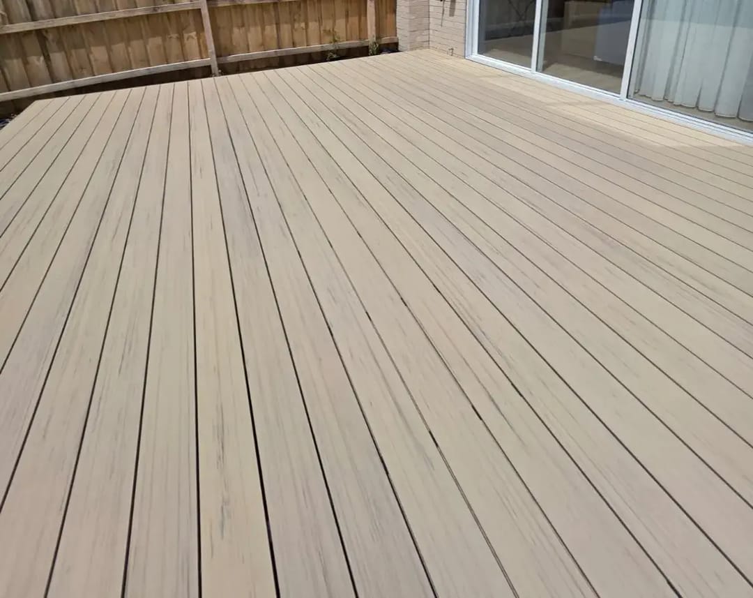 Open backyard deck in pale grey-beige CleverDeck Xtreme Driftwood boards running to a timber fence and sliding doors