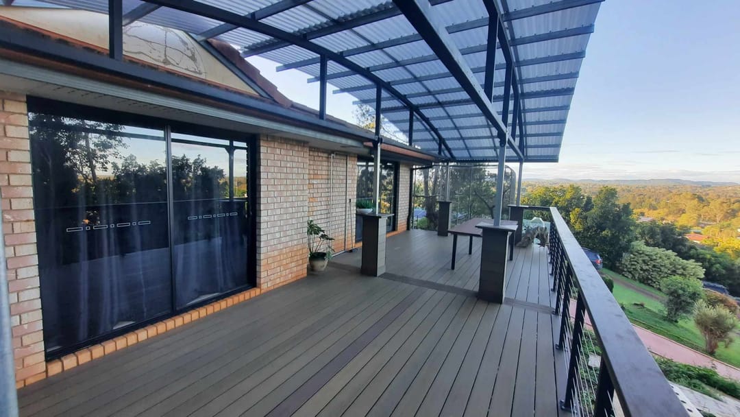 Covered composite balcony deck in a brown tone with stainless cable balustrade and wide hinterland views