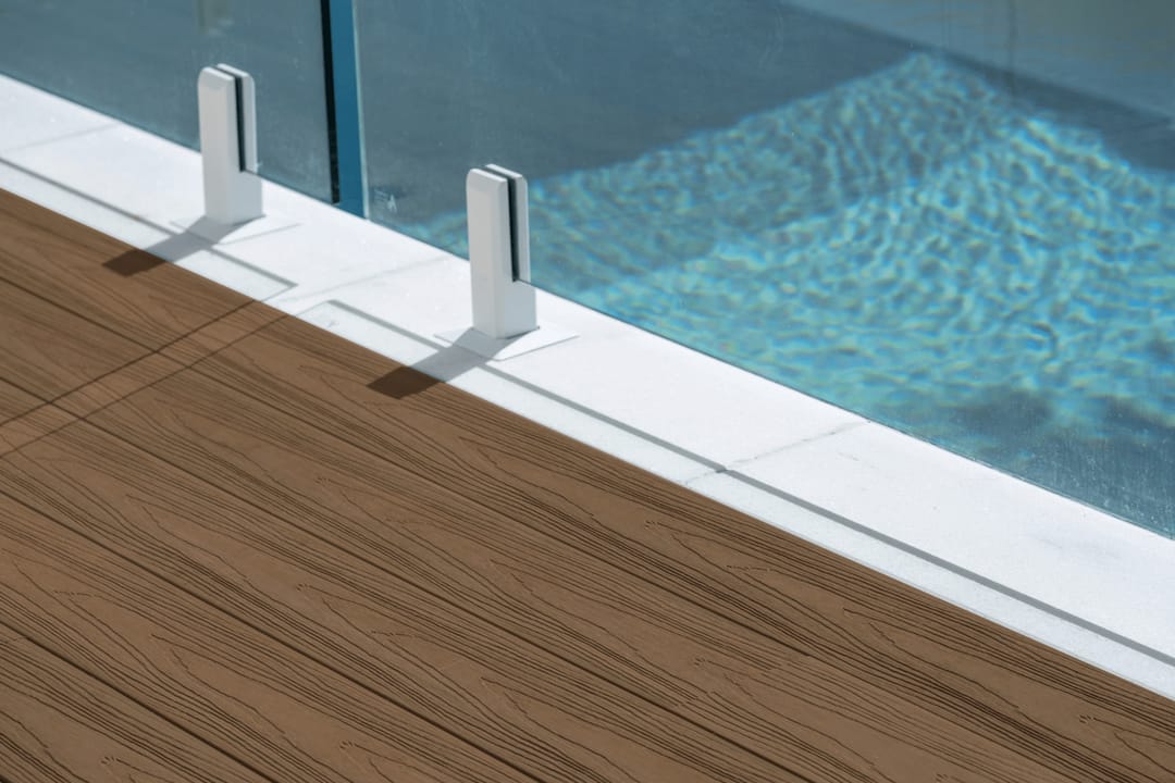 Colour visualisation of COEN Chocolate, a dark brown, as decking boards meeting a pool edge with glass fence spigots