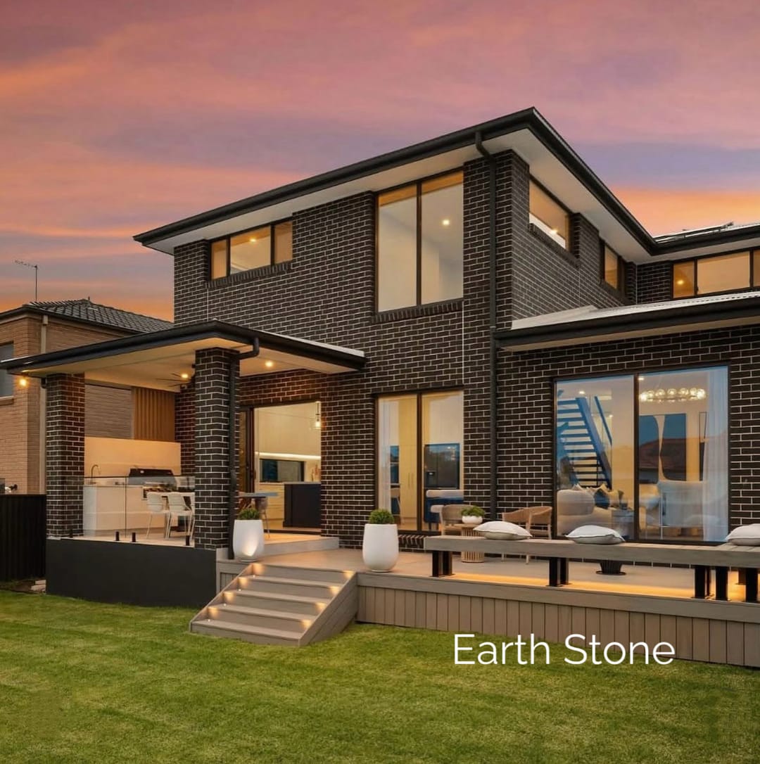 Two-storey brick home at dusk with a low Evertex Essence Earth Stone deck, outdoor bench and steps down to the lawn