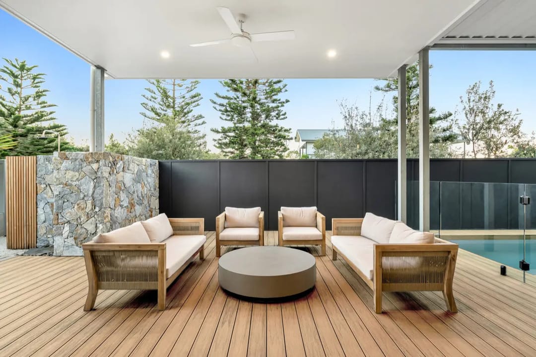 Colour visualisation of a covered alfresco deck in COEN Marine Teak, a warm mid-brown, with outdoor lounges and a stone feature wall