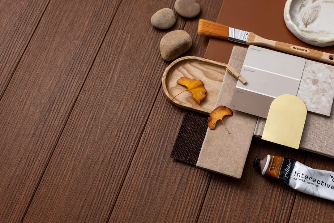 Flat lay of NewTechWood Soho Merbau boards, a rich red-brown, with stone, leather and paint colour samples