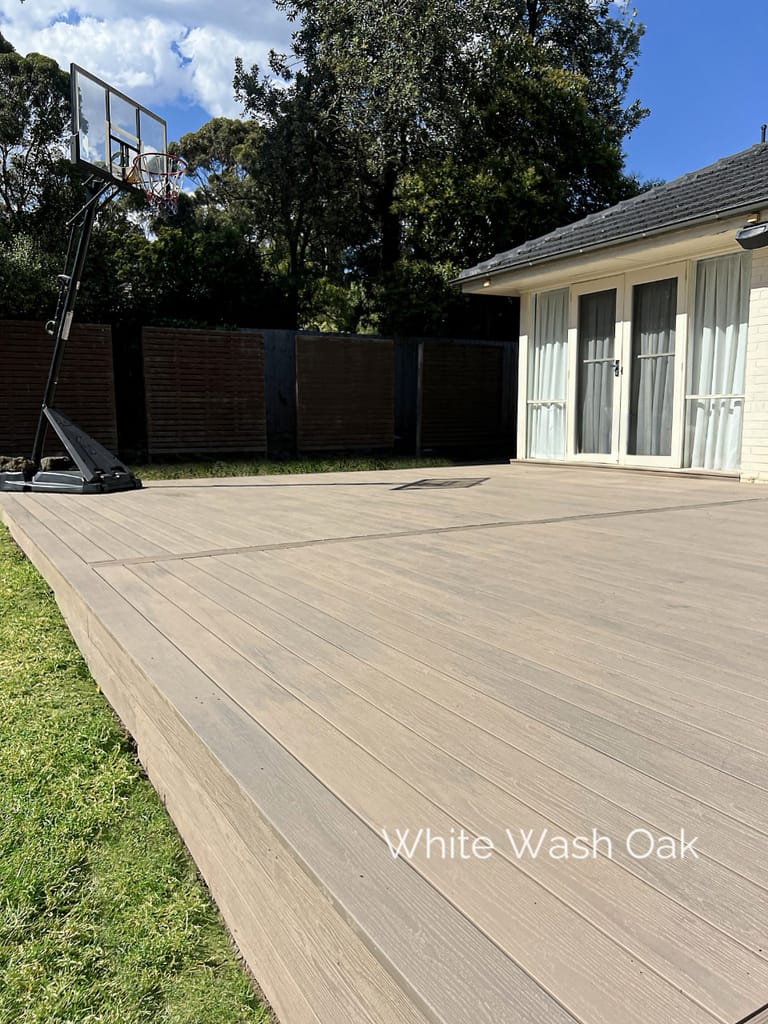 Large Evertex Pioneer White Wash Oak deck beside a lawn and a single-storey house, with a basketball hoop behind