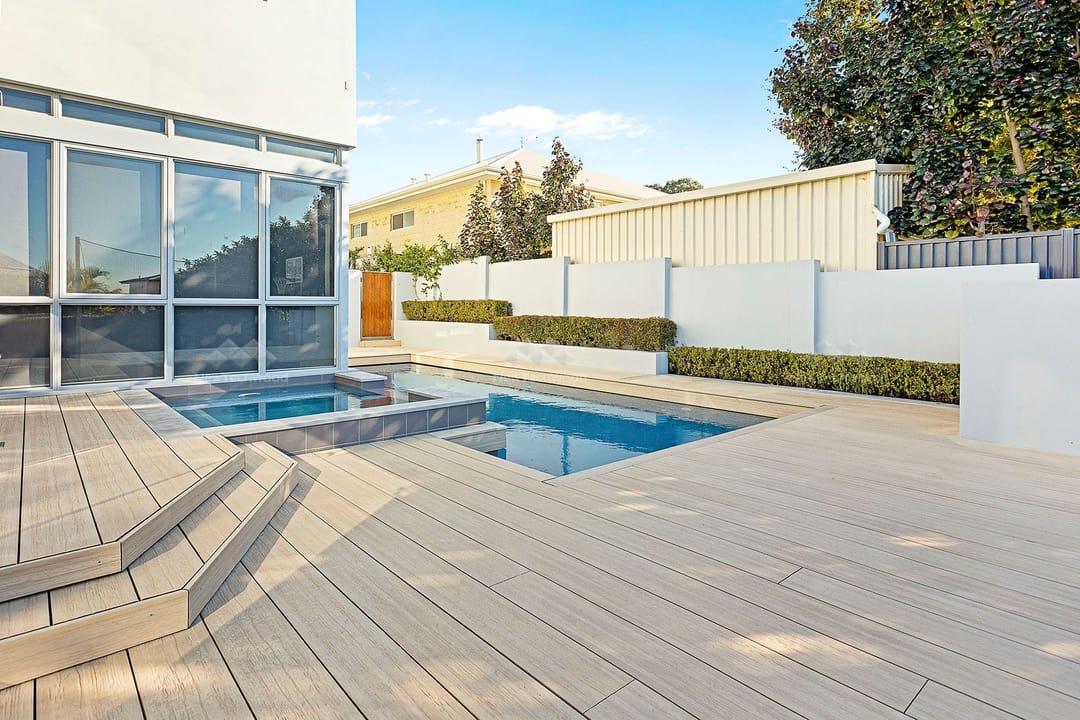 Pale NewTechWood Coastal Beech deck with steps around a pool and spa beside a modern home