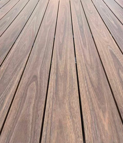 Low-angle close-up of laid Origin Spotted Gum composite deck boards with red-brown spotted gum grain