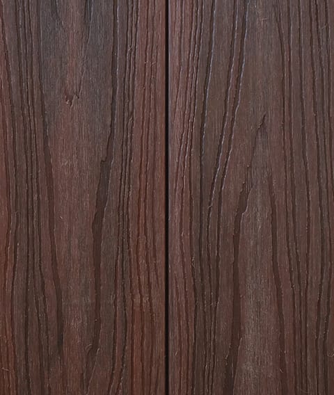 Two Modern Deck Classic Solid boards in Red Ironbark, a deep red-brown woodgrain-embossed composite surface shown close up