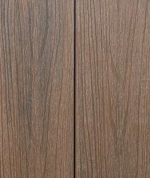 Two Modern Deck Classic Solid boards in Spotted Gum, a mid brown woodgrain-embossed composite surface shown close up