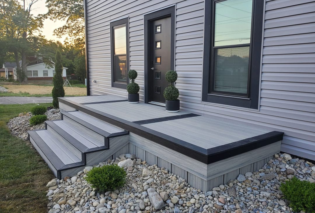 Front porch and steps with a dark Oslo picture-frame border around lighter grey decking, beside grey siding