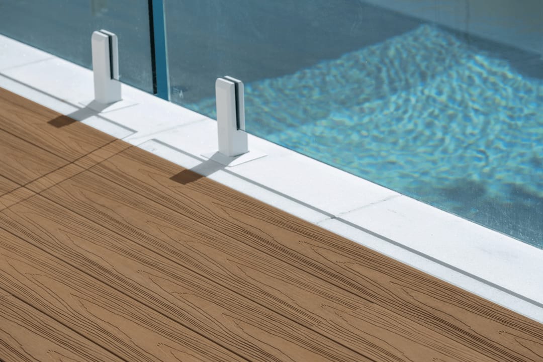 Colour visualisation of COEN Marine Teak, a warm mid-brown, as decking boards meeting a pool edge with glass fence spigots