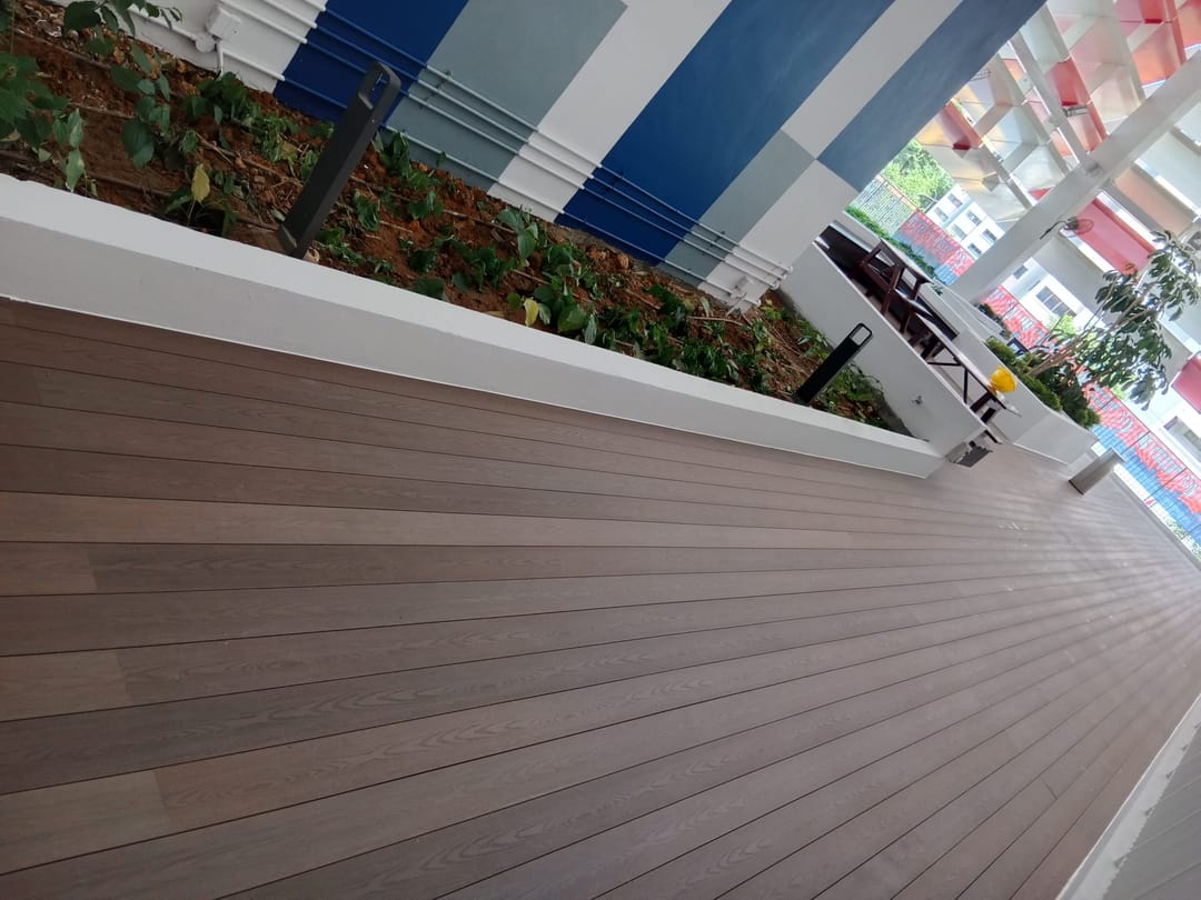 Long Biowood deck in brown boards running beside a white planter wall at an apartment building