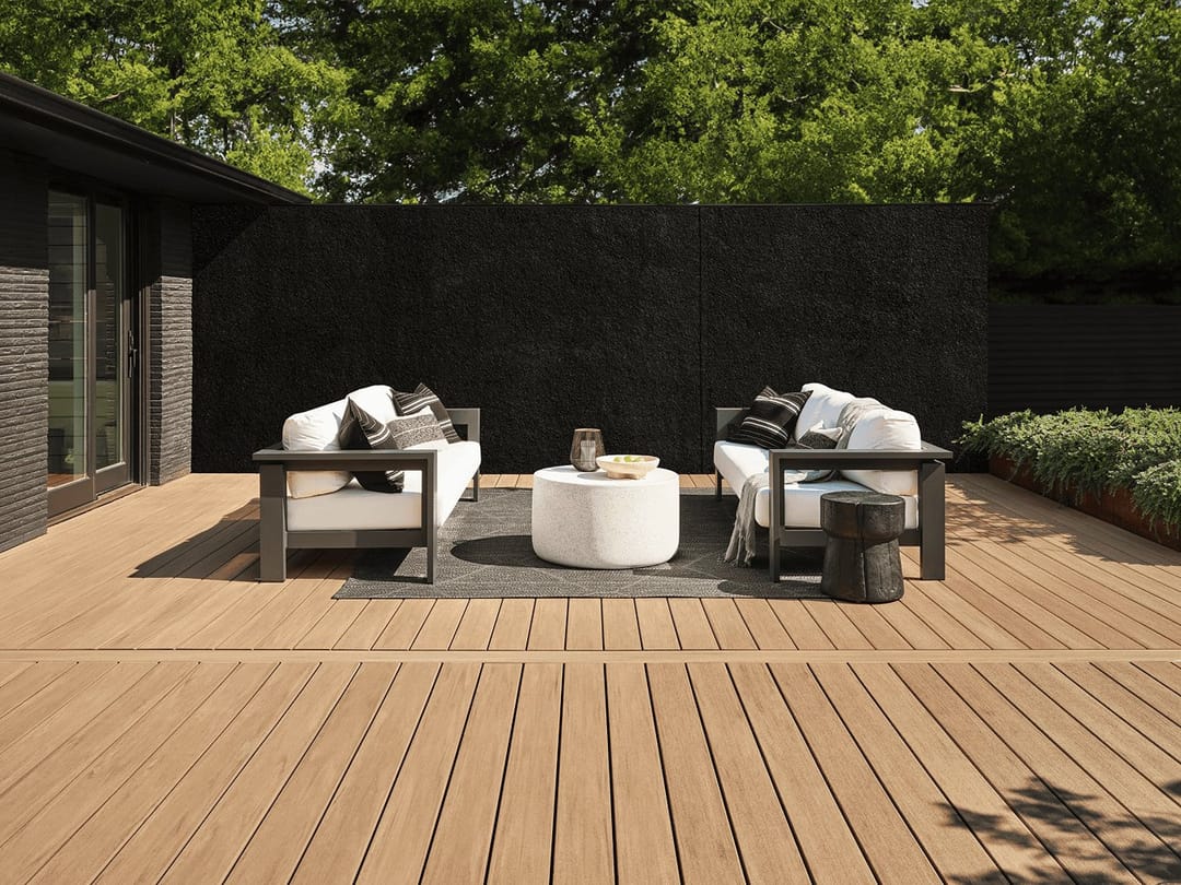 Light tan Weathered Teak deck in a walled courtyard with a pair of outdoor sofas, a round table and dark timber screen