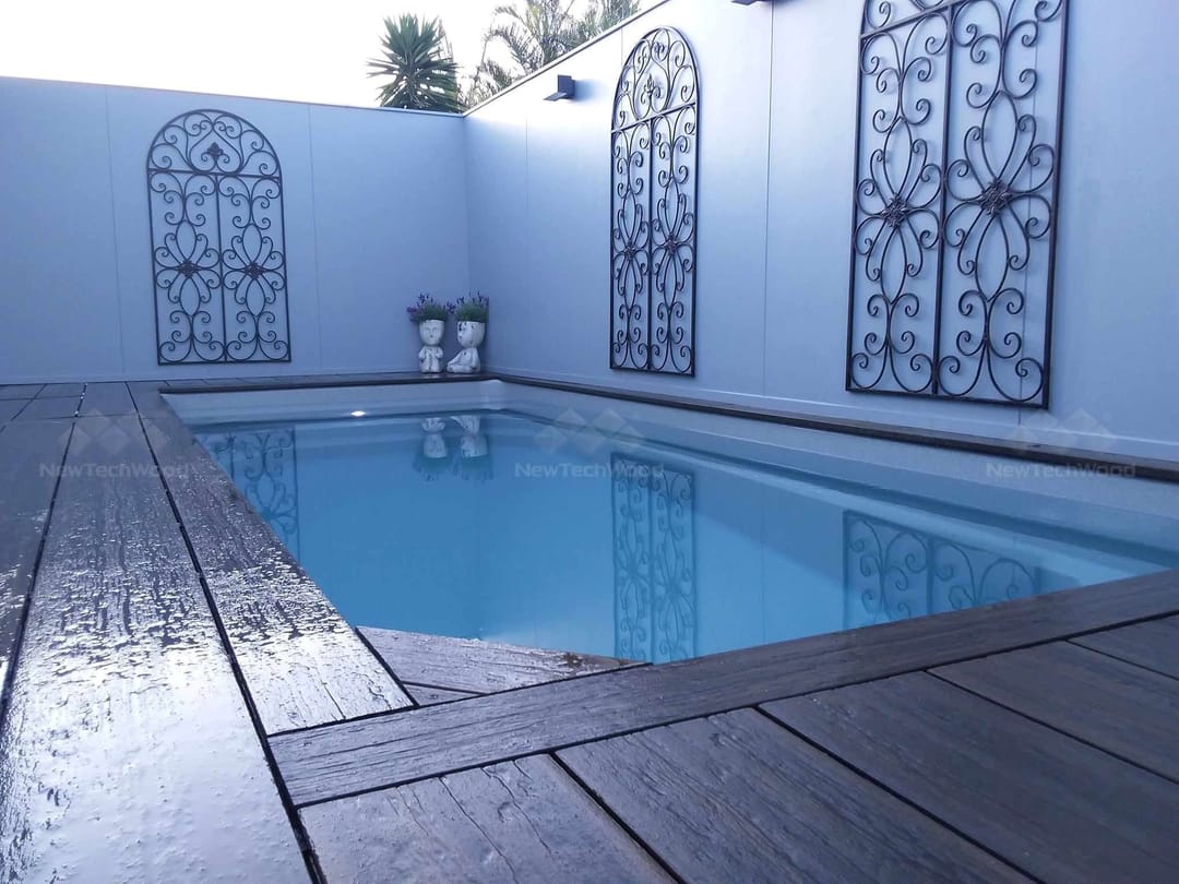 Dark NewTechWood Coastal Aged Wood deck framing a small courtyard pool with ornamental wall panels