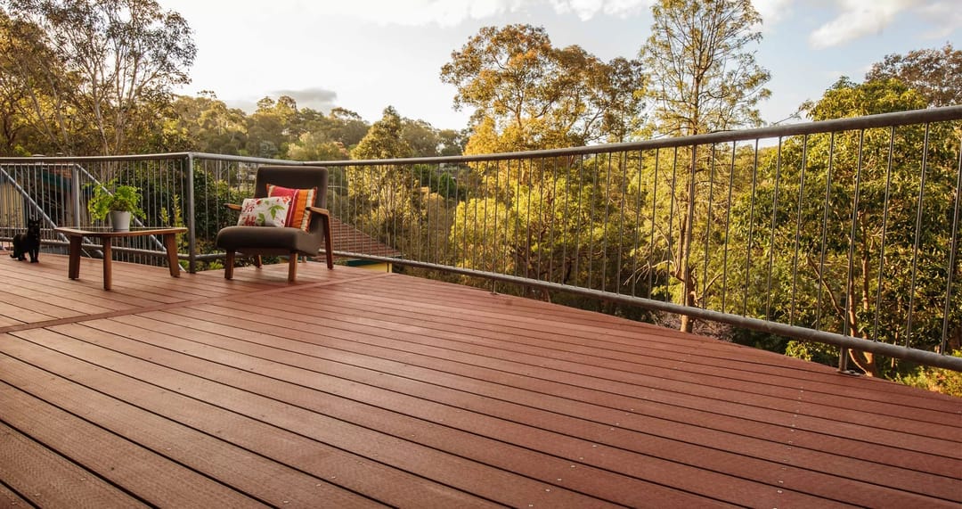 Red-brown Ekodeck Classic Red Rock deck with an outdoor armchair, looking out over gum trees in Eltham