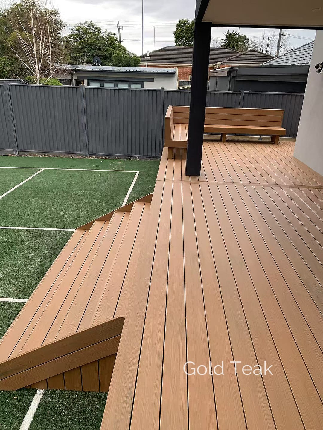Evertex Essence Gold Teak deck under a skillion roof with a built-in bench, beside a synthetic lawn sports court