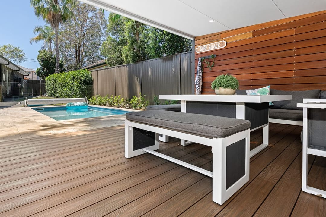Brite HD PRO Spotted Gum deck under a covered patio with a white bench table and a pool in a Picnic Point backyard