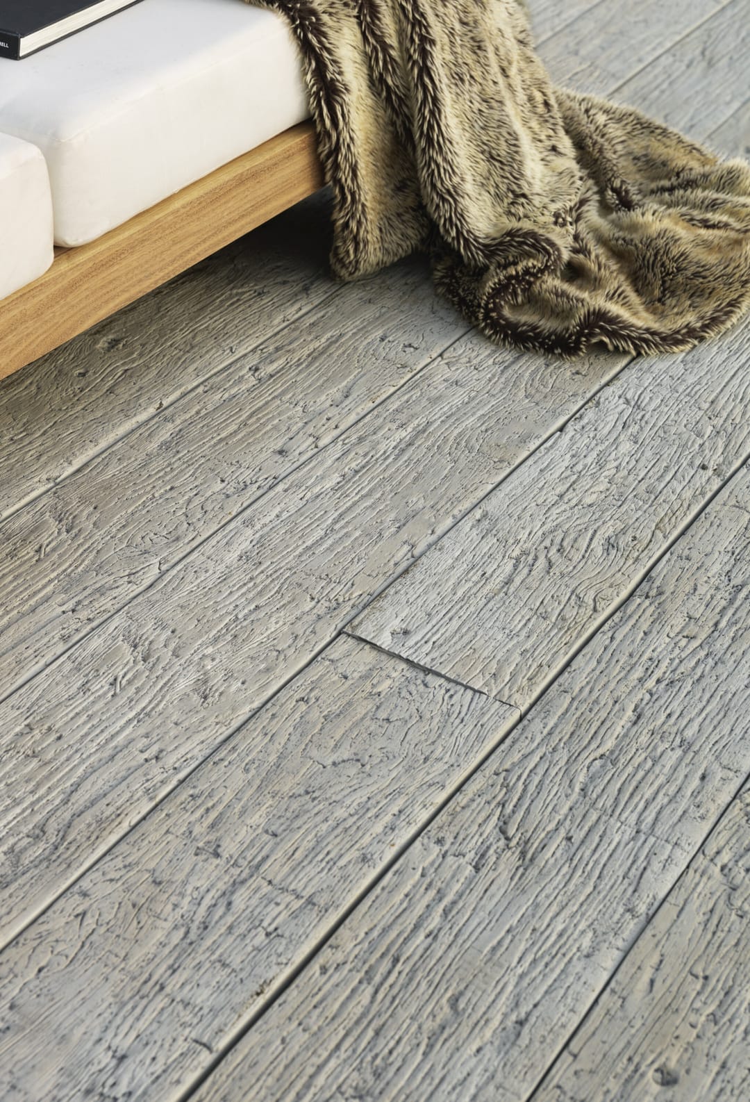 Close view of textured grey Driftwood decking with a fur throw draped from a timber outdoor sofa