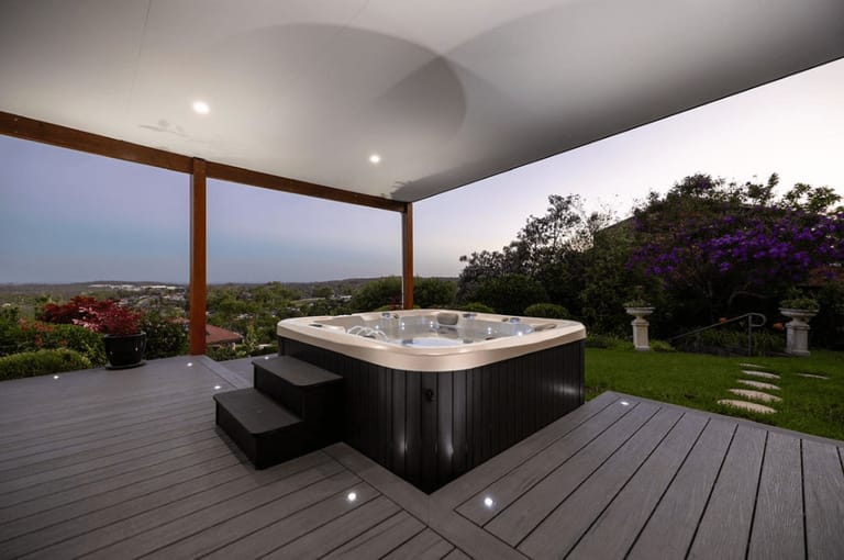 Covered ModWood Xtreme Guard Magnetic Grey deck with a hot tub and step lights at dusk