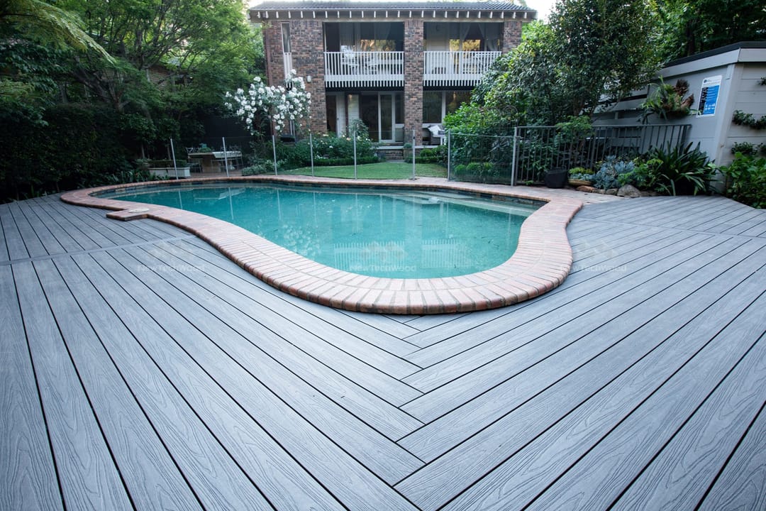 Kidney-shaped pool surrounded by NewTechWood Terrace Silver Grey decking laid in a herringbone pattern