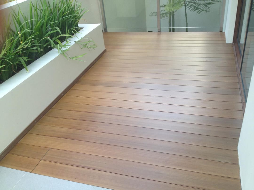 Biowood balcony deck in golden brown boards beside a white planter box and glass sliding doors