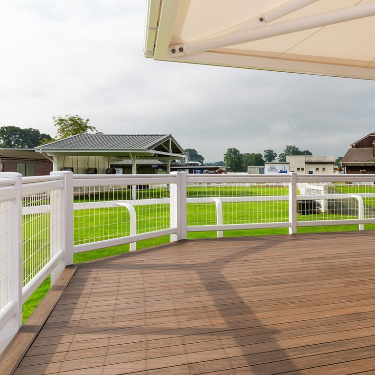 Curved verandah deck in Eva-Last Infinity Spanish Saffron with a white post-and-rail fence overlooking paddocks