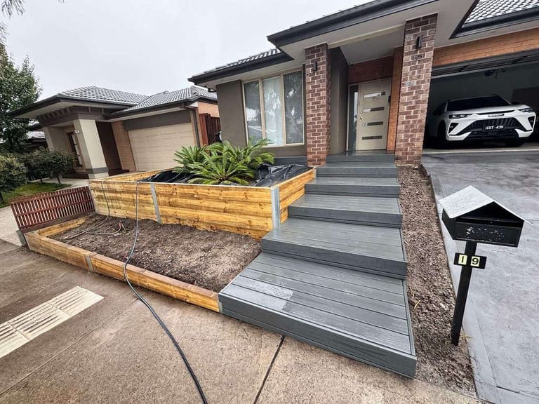 Front entry steps and landing in ModWood Xtreme Guard Charwood beside timber garden beds of a brick house