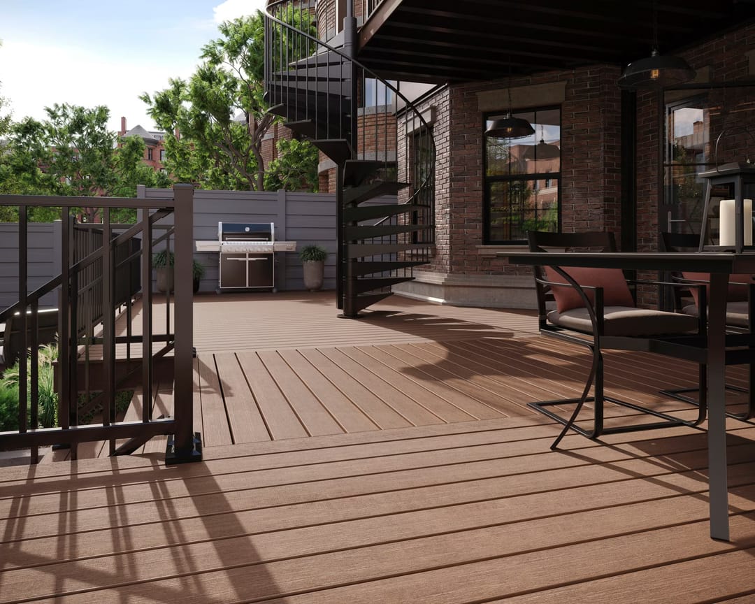 Whiskey Barrel deck with a bar table, black metal railing and spiral stair under an upper balcony beside a brick house