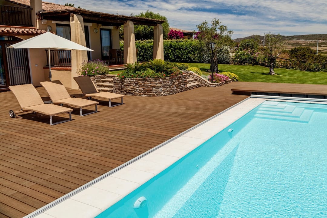 NewTechWood Avenue Teak pool deck with sun loungers and an umbrella beside a Mediterranean-style home