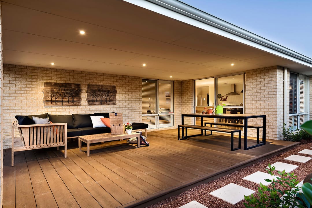 Coppered Oak deck under a covered alfresco with lounge, coffee table and dining bench beside a cream brick house