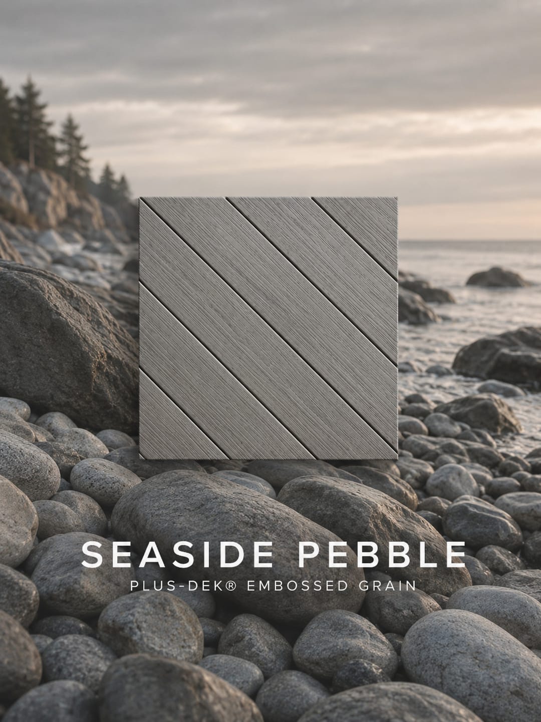 PLUS-DEK Embossed Grain colour card: a light warm grey Seaside Pebble board sample shown over a rocky beach, labelled with the colour name