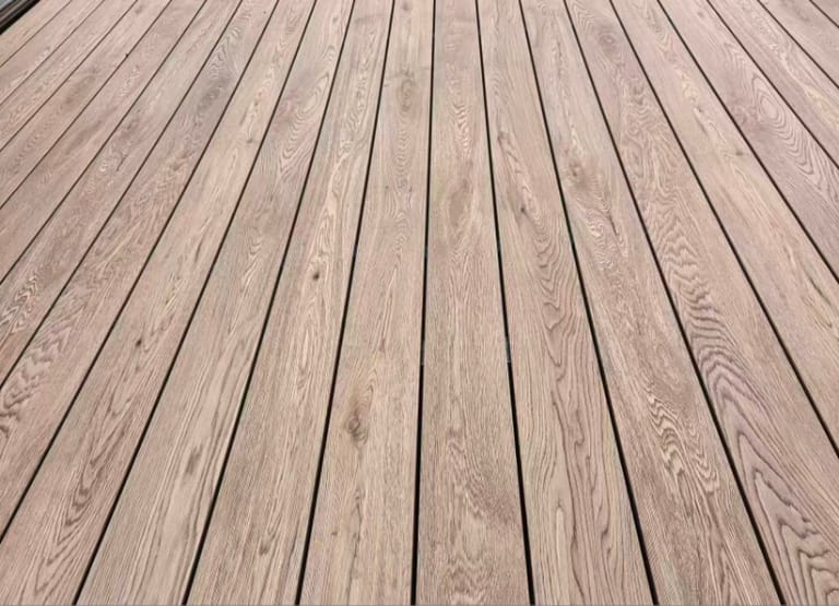Close-up of laid Origin American White Oak composite deck boards in a soft grey-brown oak grain