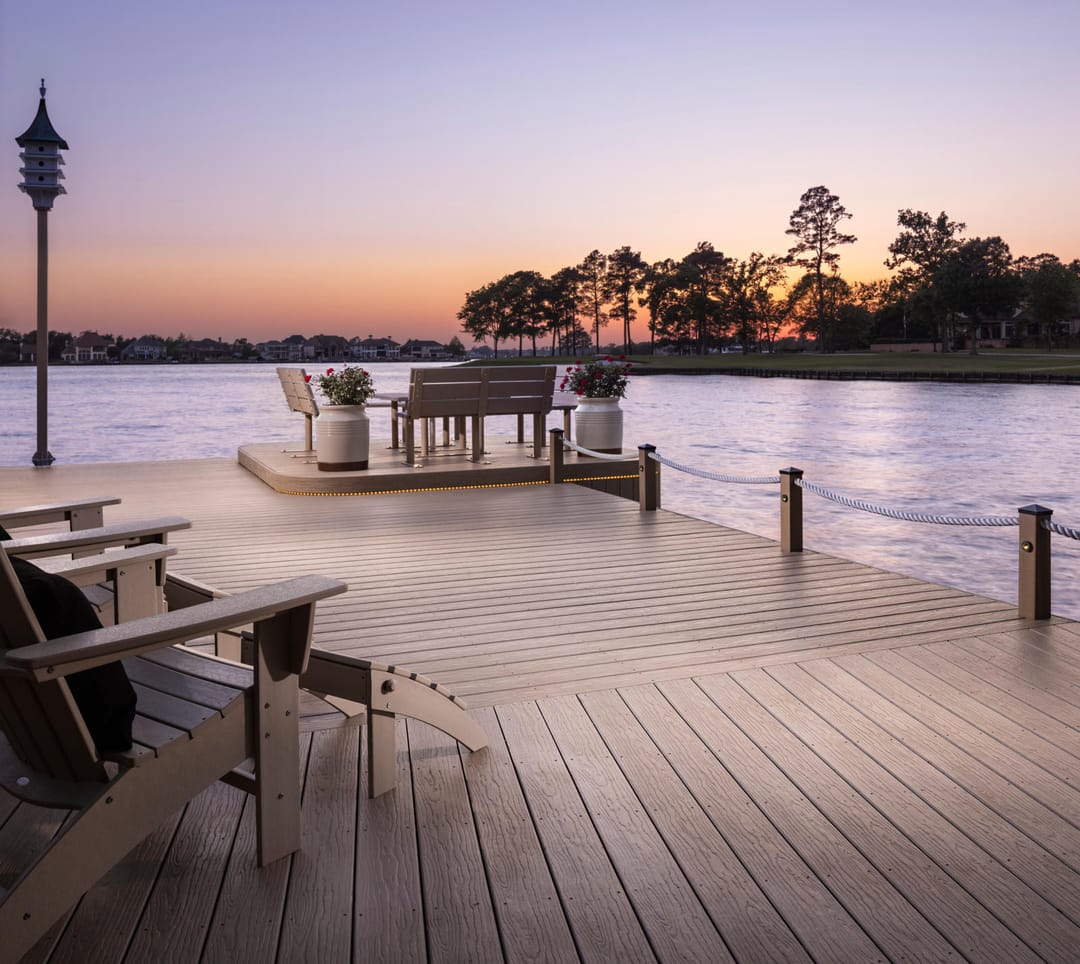 Mochaccino lakeside dock with Adirondack chairs and a lamp post, the water glowing pink at sunset