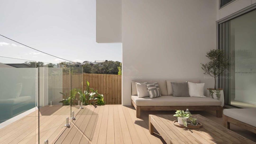 Balcony in light NewTechWood Terrace Blackbutt decking with frameless glass balustrade and an outdoor sofa