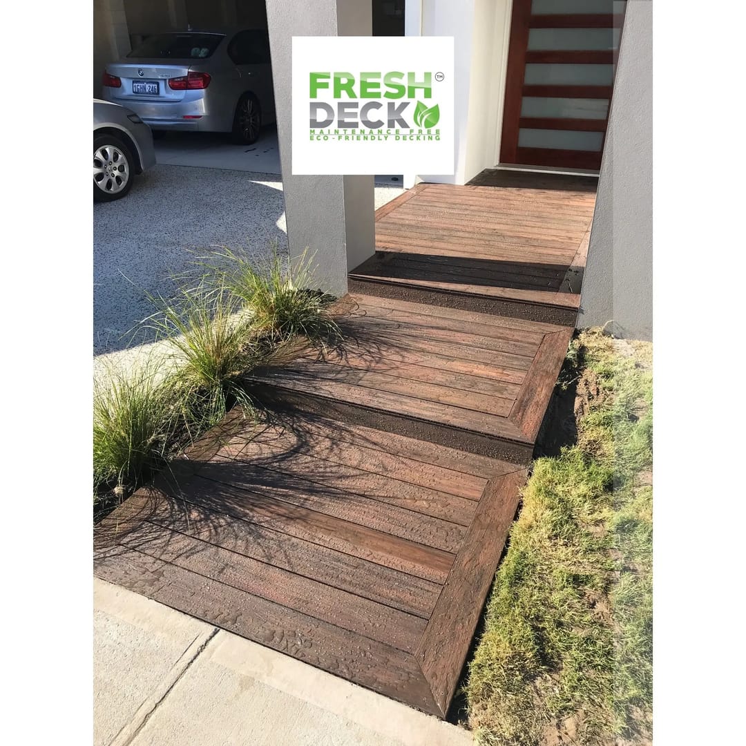 Dark brown FreshDeck composite entry path with framed edges leading to a front door, ornamental grasses alongside