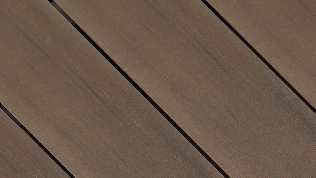 Close-up of Outdure CasaDeck Walnut MixDure composite deck boards laid on the diagonal, in mid walnut brown