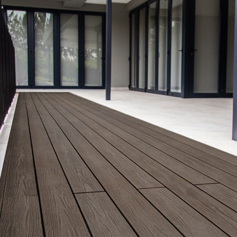 Covered patio deck in dark Eva-Last Apex PLUS Hawaiian Walnut boards outside a wall of black-framed glass doors