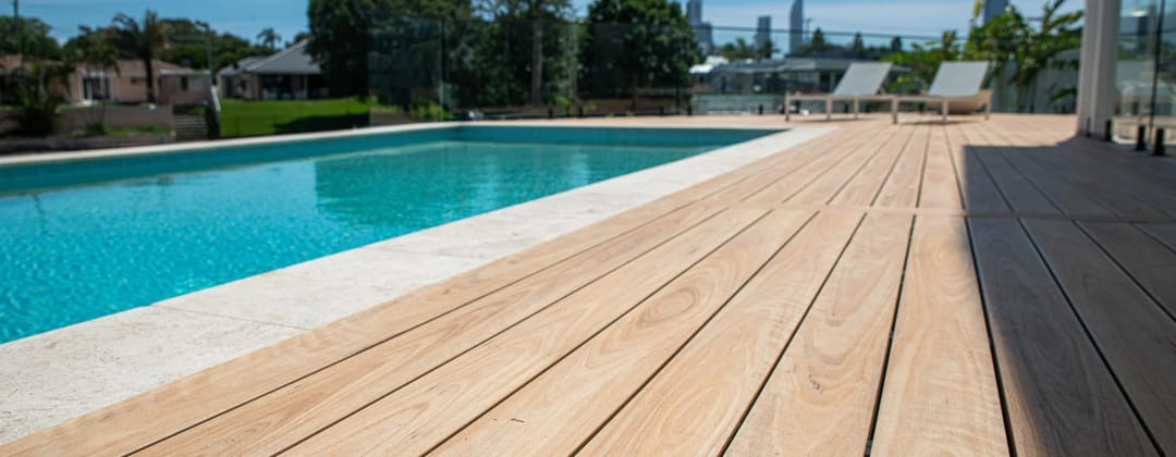 Origin composite deck running beside a blue swimming pool with sun loungers and city towers in the distance