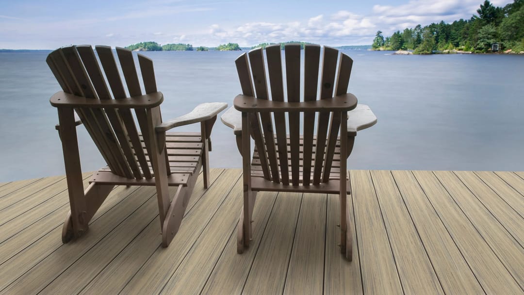 Two brown Adirondack chairs on a light Tahiti dock looking out over a calm lake