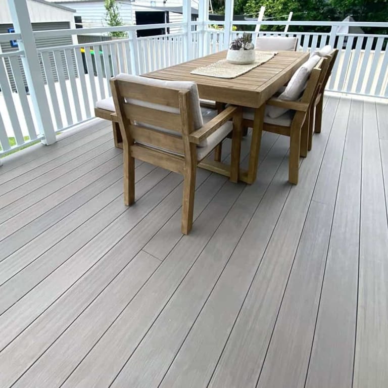 Covered verandah in Sun Decking Elite Oak, a pale grey-brown board, with a timber dining setting and white railing