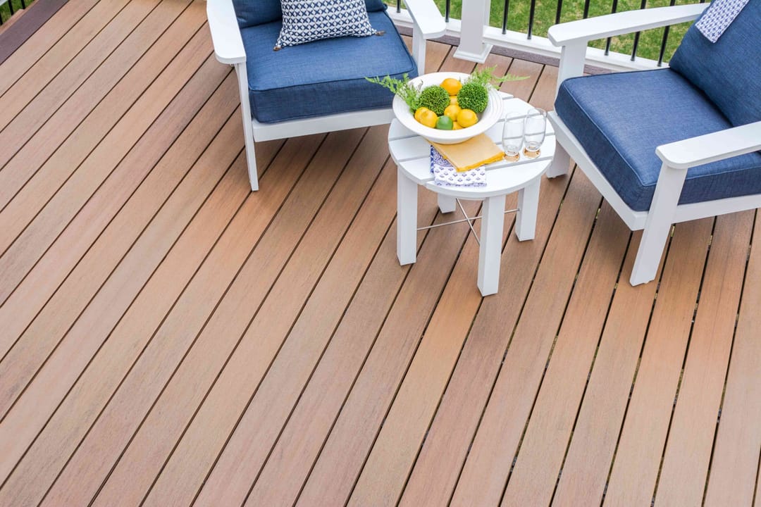Spotted Gum deck with white chairs, navy cushions and a round table with yellow flowers beside a white railing