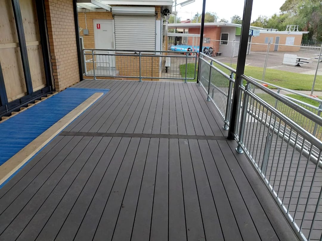 Covered walkway decked in CleverDeck Original Slate Grey at a swimming club, with steel balustrades and a blue mat