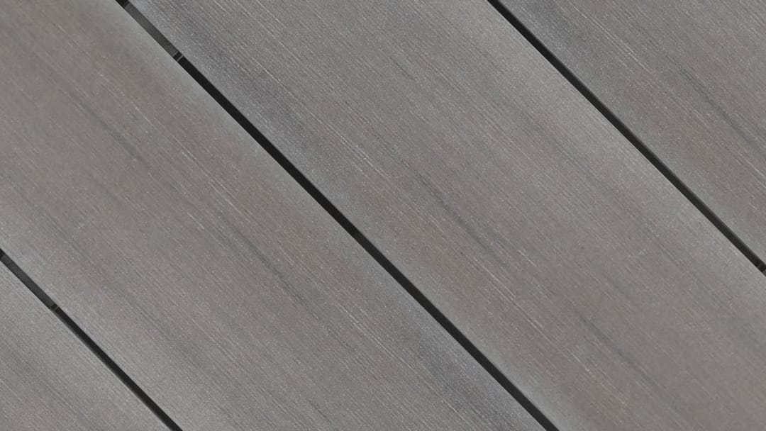 Close-up of Outdure CasaDeck Ash MixDure composite deck boards laid on the diagonal, in streaky grey