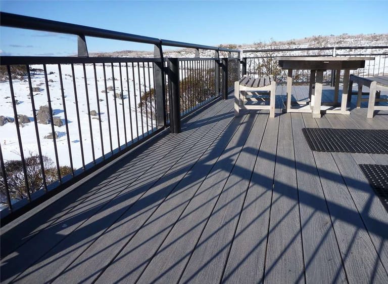 Grey ModWood Flame Shield Silver Gum deck with black balustrade and outdoor tables, looking over snowy alpine country