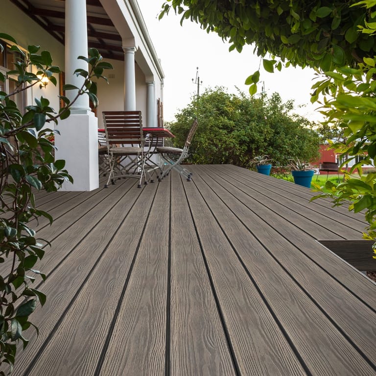 Verandah deck in Eva-Last Apex PLUS Brazilian Teak running past white columns to a garden with outdoor chairs