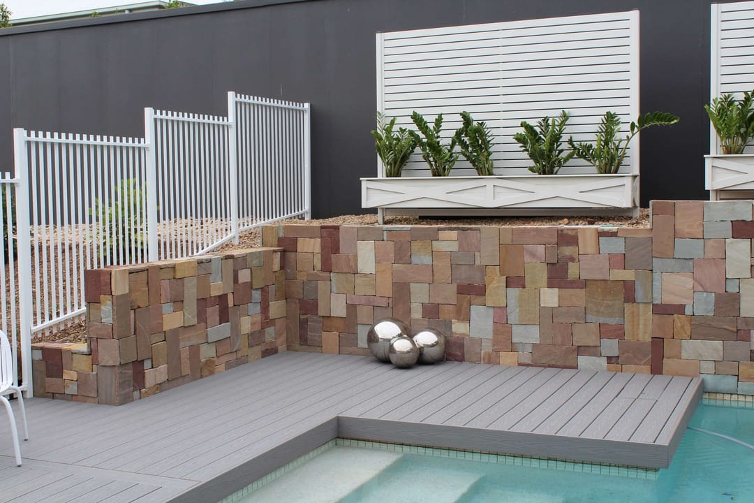 Grey Cottage deck edging a plunge pool, with a stone-clad wall, planter boxes and pool fencing