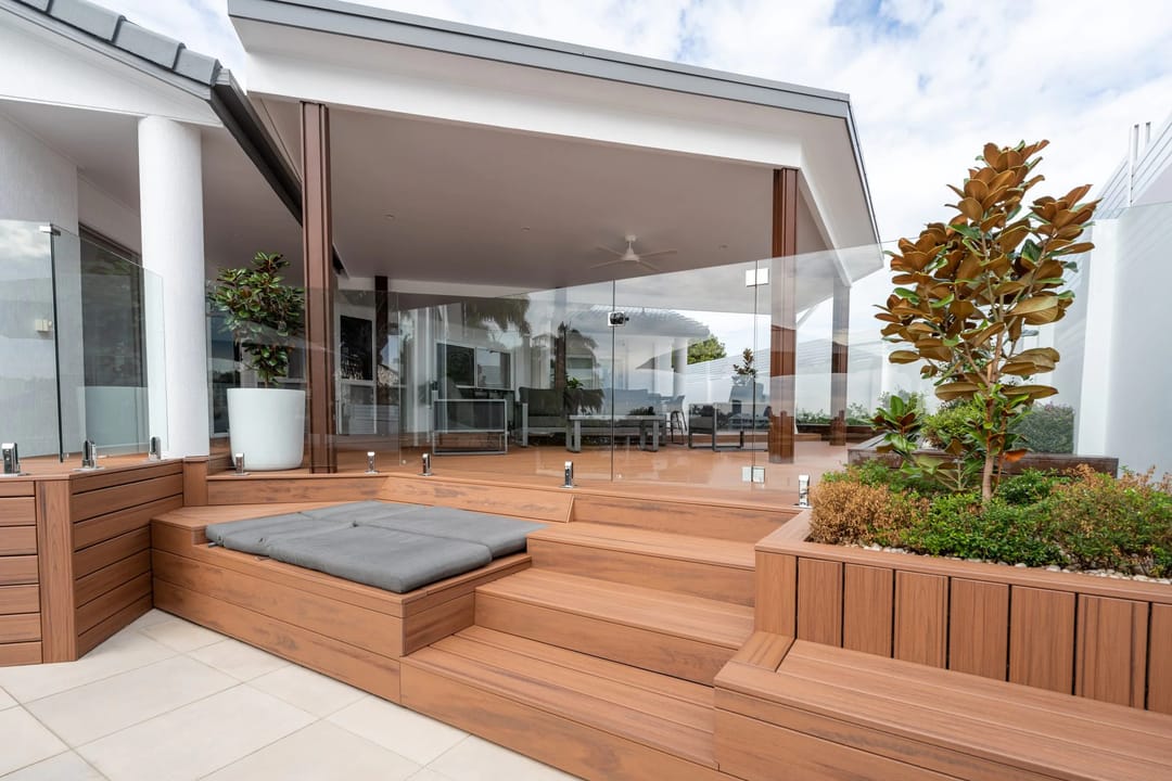 Tiki Torch decking with built-in bench seat, planter boxes and steps up to a covered alfresco with glass balustrade