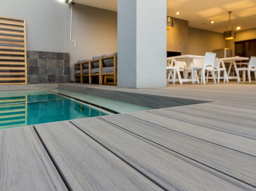 Light grey Eva-Last Infinity Caribbean Coral deck along a narrow lap pool, open to an indoor dining area