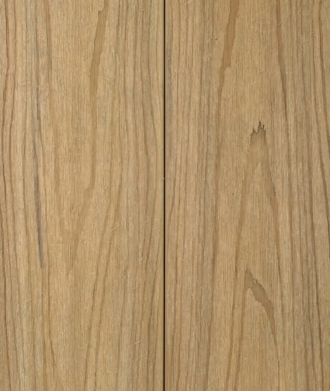 Two Modern Deck Classic Solid boards in Blackbutt, a light honey-toned woodgrain-embossed composite surface shown close up