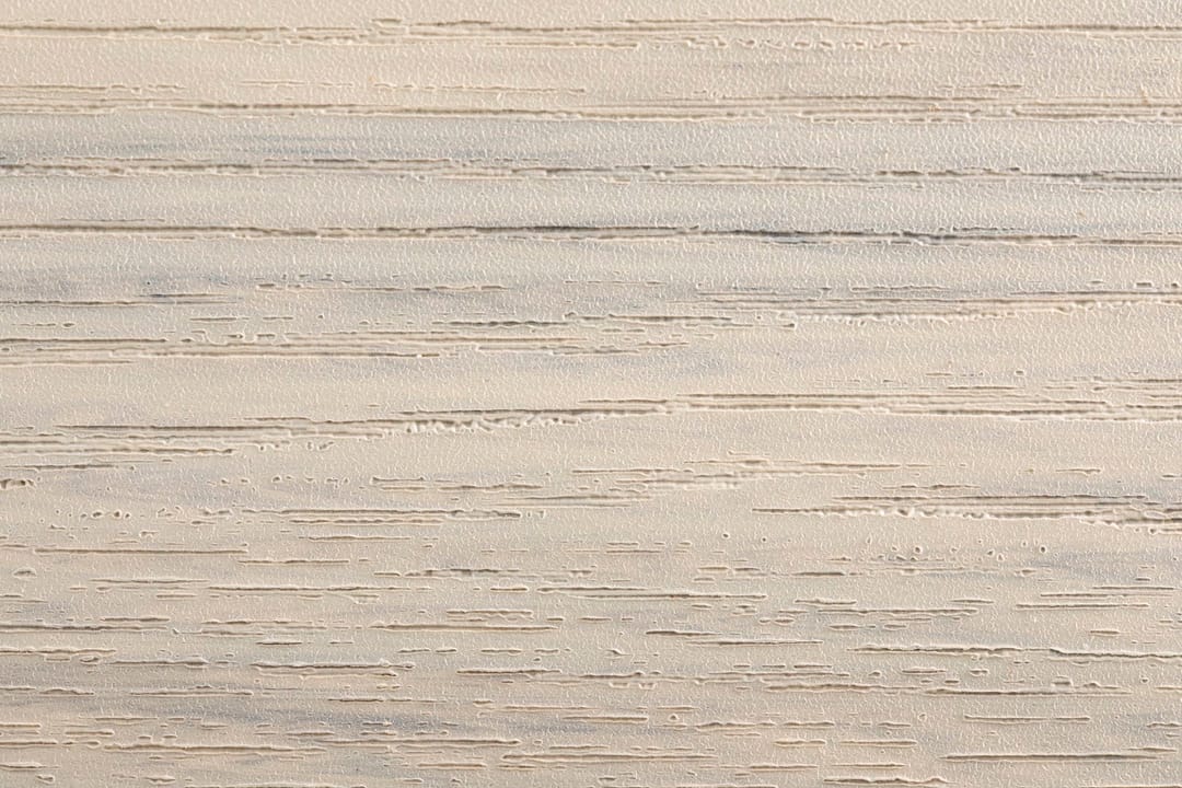 Close-up of an Evertex Supreme Max Pale Oyster board surface showing its embossed wood-grain texture in light oyster beige